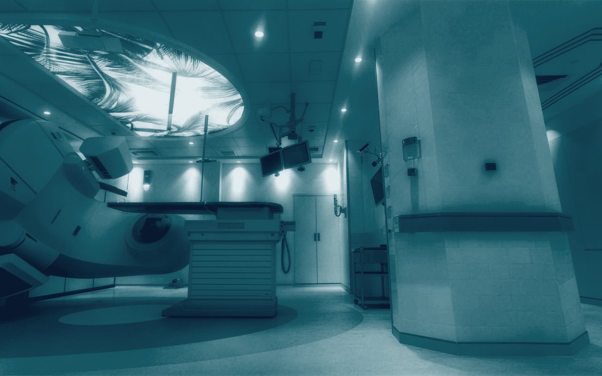 A linear accelerator treatment room with a backlit ceiling panel.